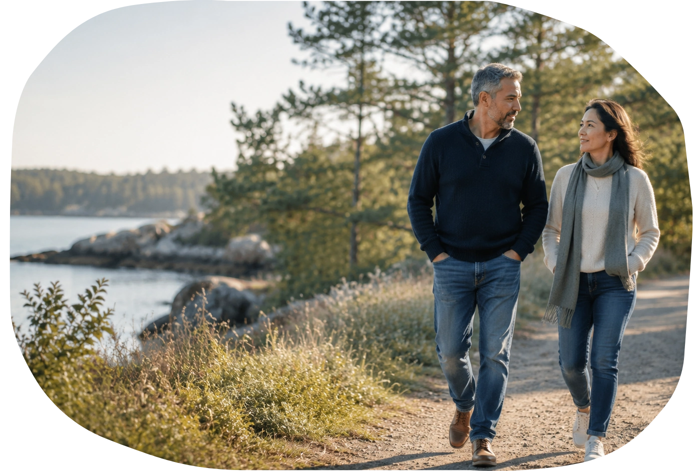 A midlife couple walking peacefully together along a sunlit coastal path.
